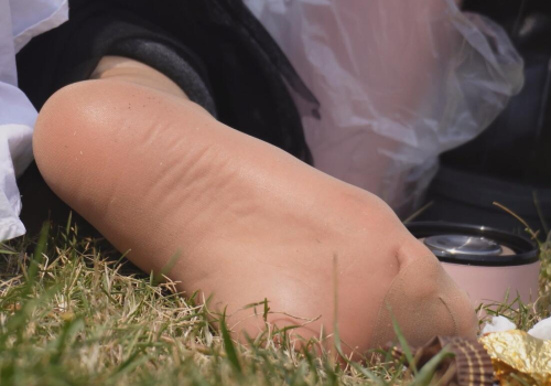 The lady takes off her boots and relaxes her feet on the lawn