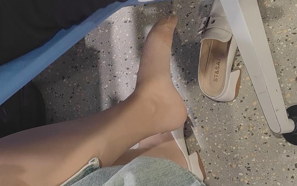The pretty lady in white kitten heels dangling shoeplay