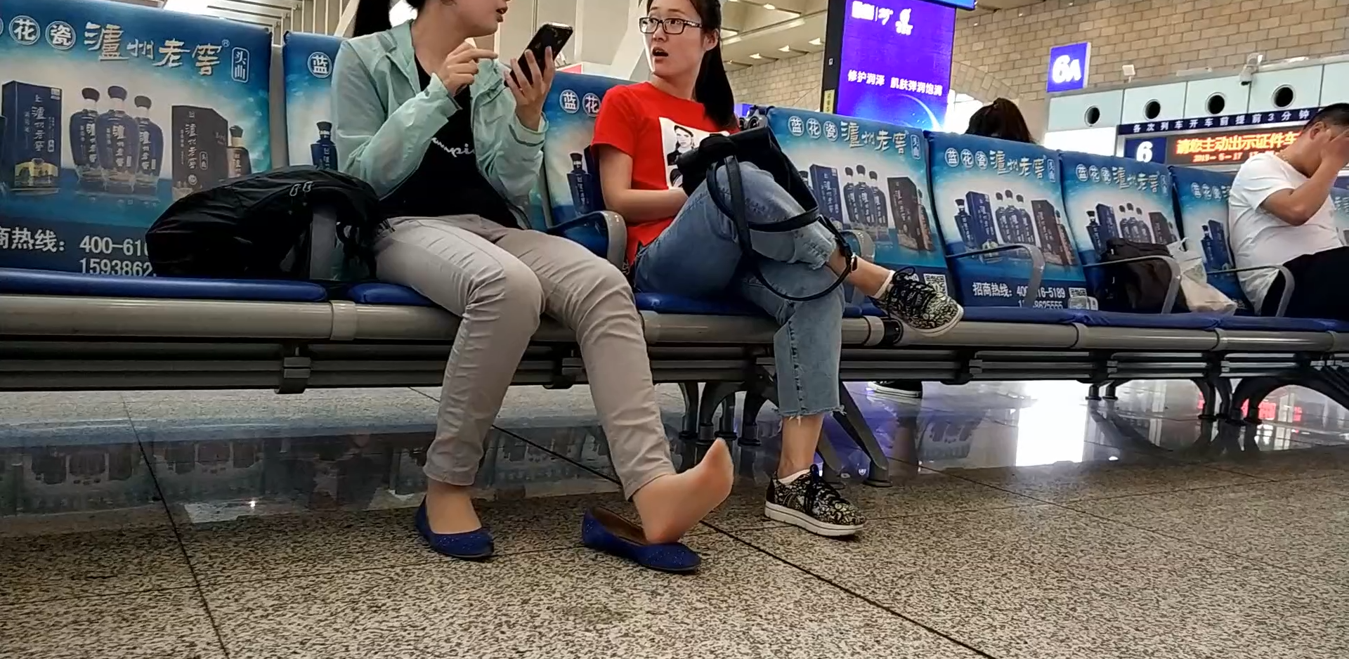 Lady relax her tired feet when waiting for the train in railway station lounge 2