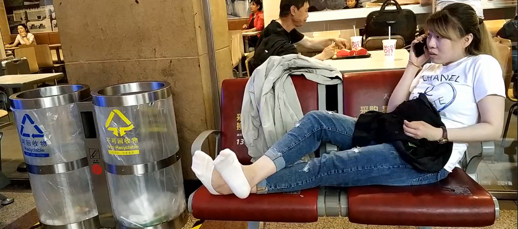 Lady put her tired nylon feet on the chair when waitting for a train