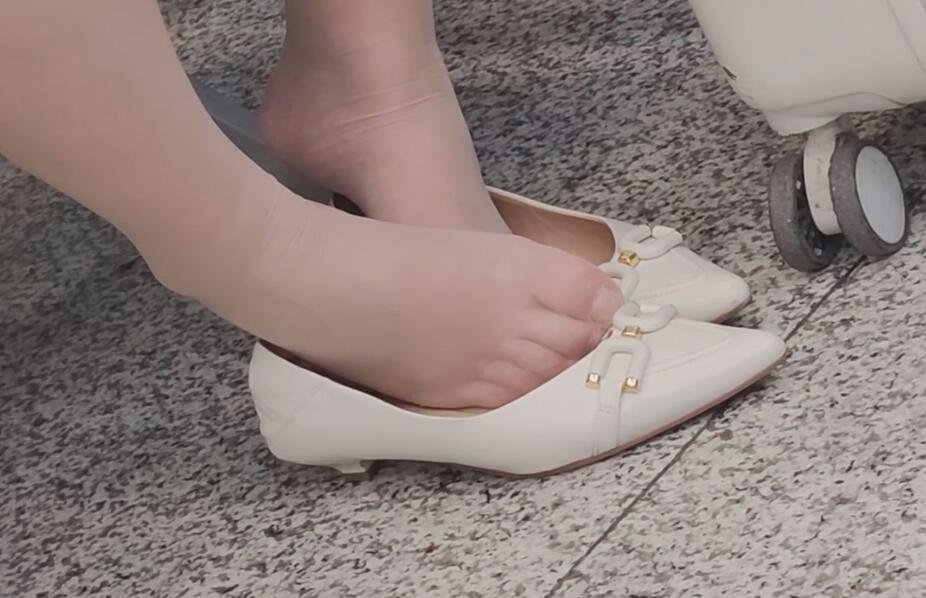 The lady in white heels dipping shoeplay in the waiting hall of the railway station